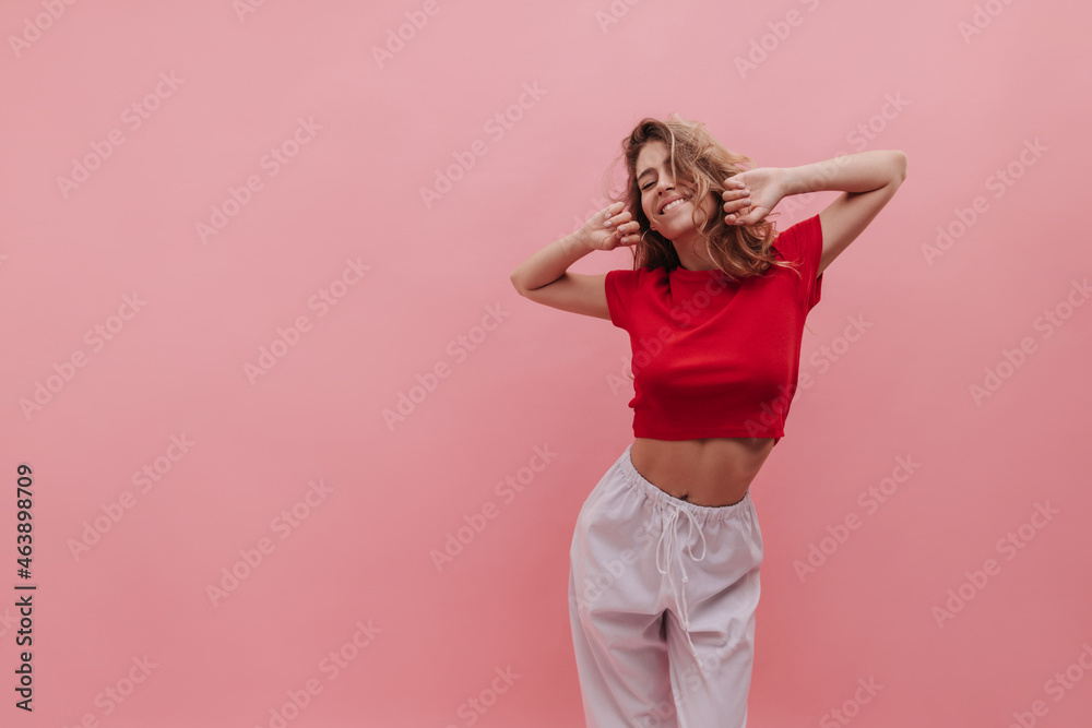 Medium shot of young Ukrainian girl morning bird enjoying sunrise against pink background. Woman with blond wavy hair and natural make-up stretches after waking up early. Beauty and youth concept