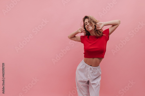 Medium shot of young Ukrainian girl morning bird enjoying sunrise against pink background. Woman with blond wavy hair and natural make-up stretches after waking up early. Beauty and youth concept