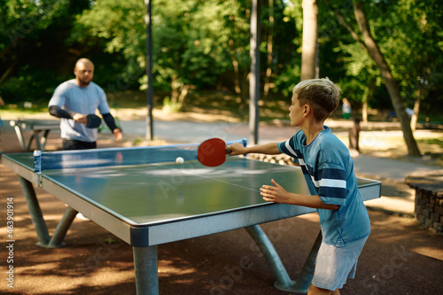 Father and son play table tennis outdoors photo