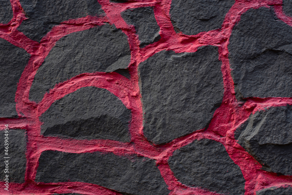 Fragment of a stone fence from a black big stone with bright pink plaster, a beautiful stone background for various needs. Close up Fragment of a stone fence from a black big stone with bright pink plaster, a beautiful stone background for various needs. Close up