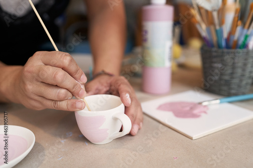 Keramik malen, weiß und rosa, mit Pinsel und Frauenhand