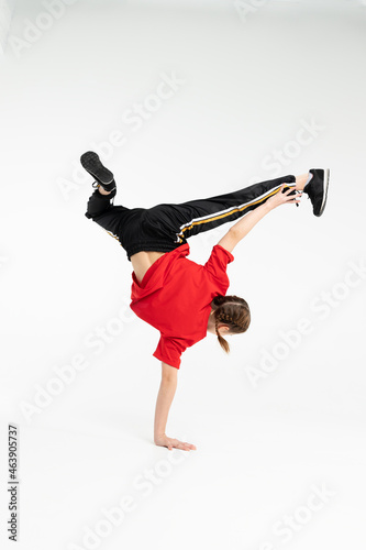 Russian b-girl break dancer in red t-shirt in white background doing stunt hand stand turning back to the camera