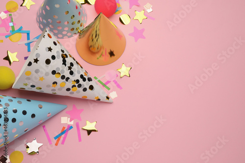 Flat lay composition with party hats and other festive items on pink background. Space for text