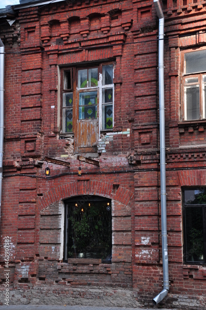 Old red brick house. Wooden balcony door with peeling paint.