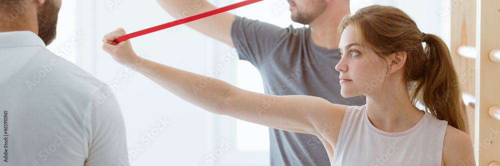 Young man and a woman stretch their arms with the use of tapes d Young man and a woman stretch their arms with the use of tapes d