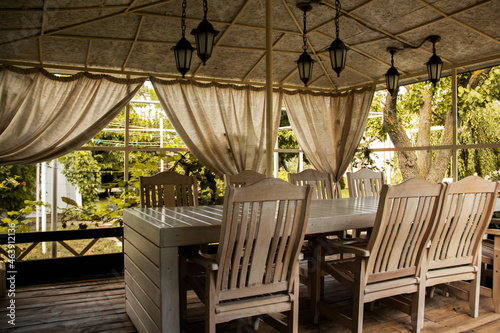 Wooden white gazebo in the summer garden. White garden furniture. Rest and relaxation in the private garden. Alcove