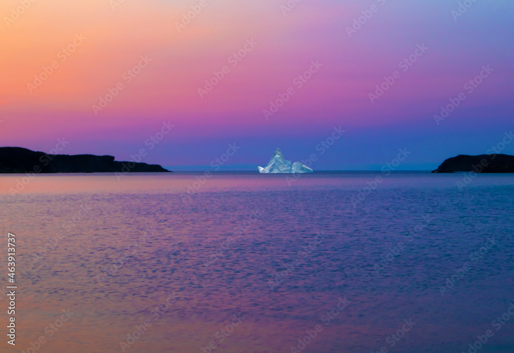 Pastel colored sunset over an iceberg at sea