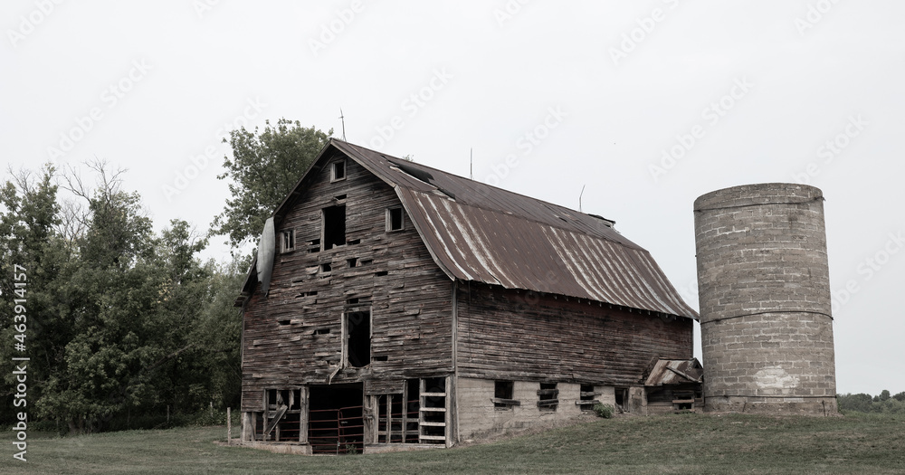 Dreary old dilapidated farm barn and silo with overcast sky in northern Minnesota Dreary old dilapidated farm barn and silo with overcast sky in northern Minnesota