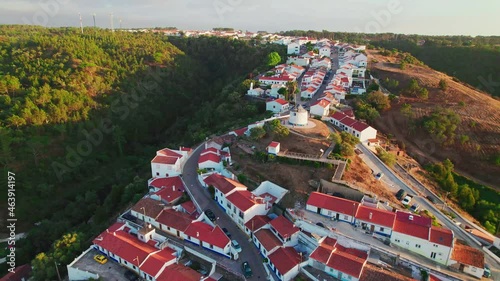 Scenic sunset over a Portuguese village with traditional colourful houses in 4K. Whitewashed traditional windmill in Odeceixe, Aljezur, Portugal, Algarve, near the Nature Park.