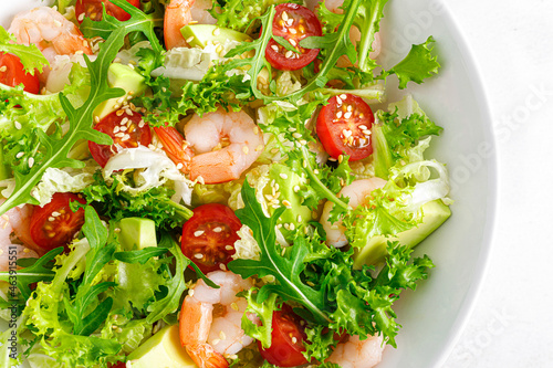 Shrimps, tomato and avocado summer vegetable salad with fresh lettuce, rocket and sesame. Healthy eating. Keto, ketogenic diet. Top view.