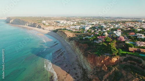 Aerial view of holiday luxury houses by the rocky cliffs of Lagos, Algarve in 4K. Stunning sunrise above view from the colourful turquoise ocean in Portugal of Ponta da Piedade and Lagos town.