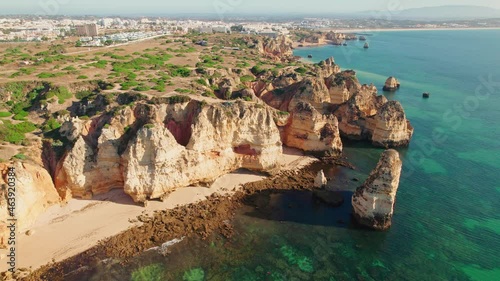 Aerial view of Ponta da Piedade - Famous Tourist attraction in Lagos, Algarve. A group of rock formations of yellow-golden clifflike rocks with caves and grottos along the coastline of Portugal in 4K. photo