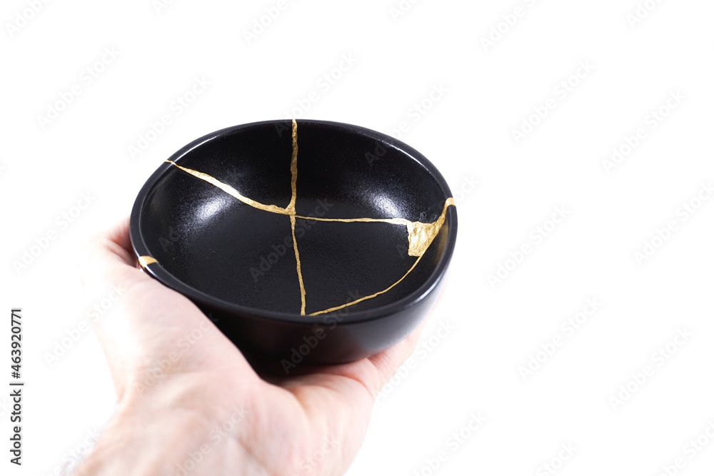 Isolated Japanese kintsugi black bowl restored with real gold , black pottery with gold cracks Isolated Japanese kintsugi black bowl restored with real gold , black pottery with gold cracks