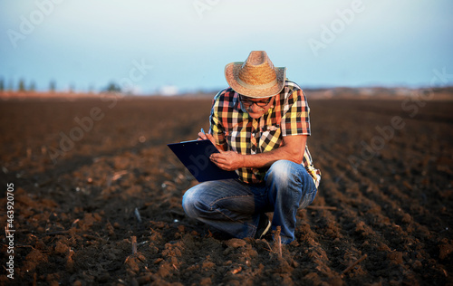Farmer controls the soil and making a notes after plowing in the field. Agricultural concept
