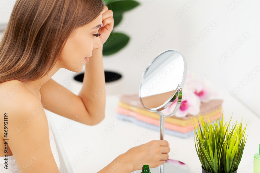 Young beautiful woman making make-up near mirror Young beautiful woman making make-up near mirror