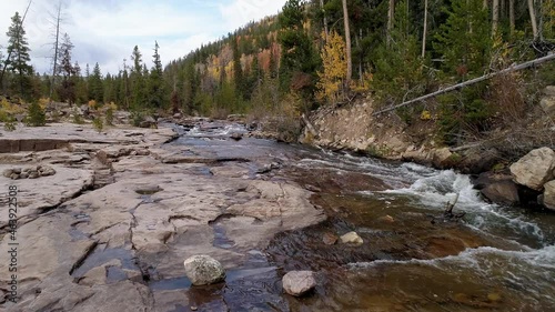 Flying upstream over the Provo river during the Fall in the Uinta Mountains rising up over the trees. photo