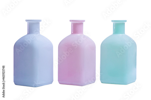 Three glass bottles, green, pink, and mint green isolated on white background