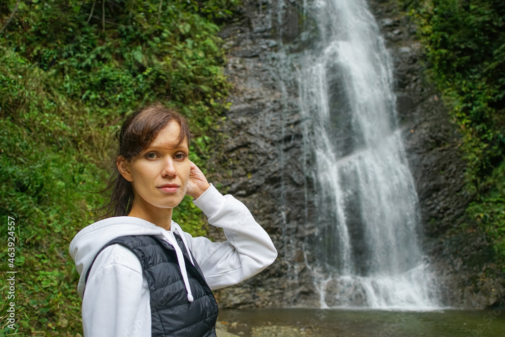 Young woman standing in front of waterfall. People travel enjoying nature, break from city