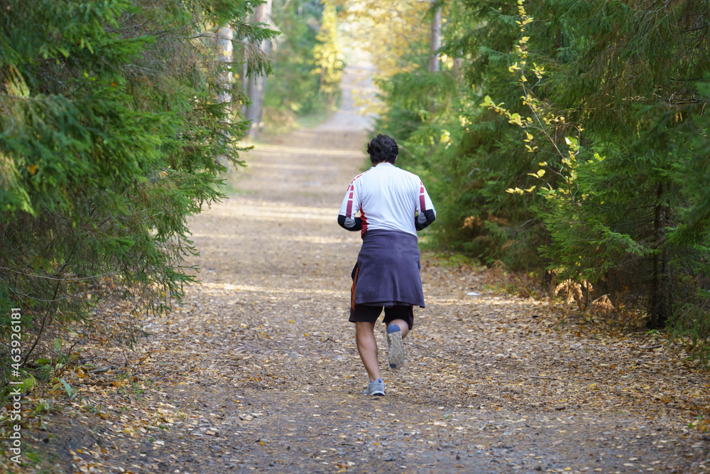 Athlete man running in autumn forest during cold foggy morning. Male jogger training outdoors before marathon in nature park jogging along trail. Fit sportsman exercising in october fall woods alone Athlete man running in autumn forest during cold foggy morning. Male jogger training outdoors before marathon in nature park jogging along trail. Fit sportsman exercising in october fall woods alone