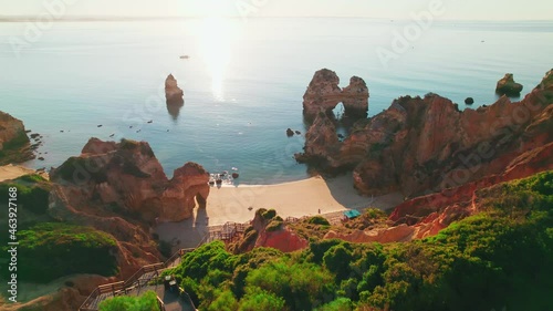 Aerial view of Praia do Camilo by rocky coastline in Lagos, Algarve, Portugal. Scenic view of Praia do Camilo from above - a tourist crowded and famous relaxing holiday beach in 4K. photo