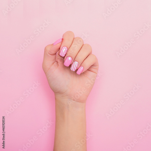 Beautiful female hand with creative manicure nails, hearts design, on pink background