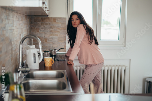 Beautiful young woman making a cup of coffee in the morning at home