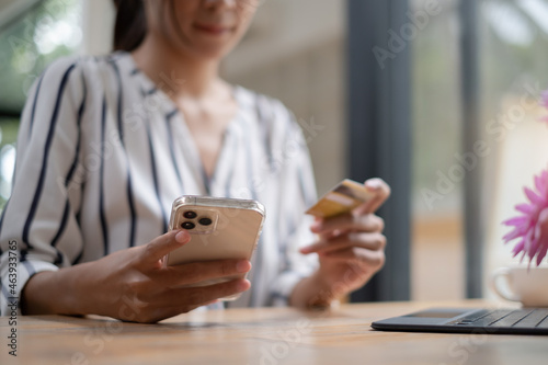 Beautiful Woman holding smartphone using ecommerce platform and enjoy with online shopping and typing credit card for fill number to payment. © itchaznong