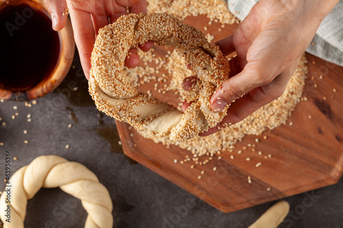 delicious Turkish bagel with sesame seeds known as susamli simit. top view image shows shaping the braided dough and making sure sesame sticks on surface photo