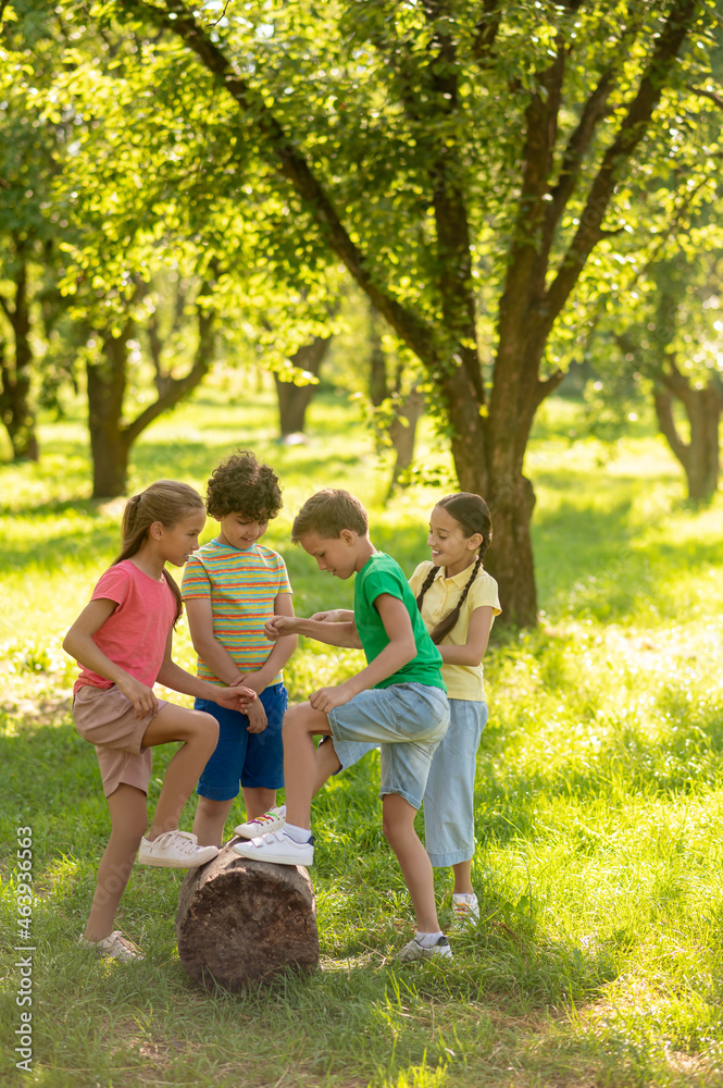 Fototapeta premium School children near stump in green park