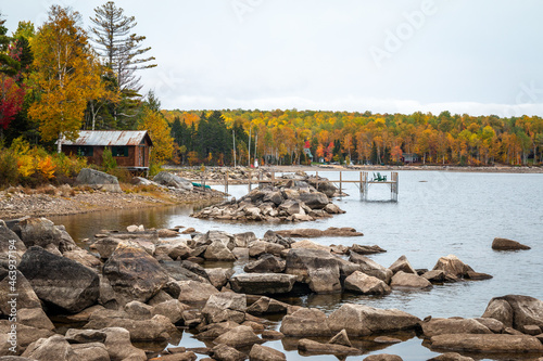 A rocky shoreline with a cabin. A wonderful scene during fall. 