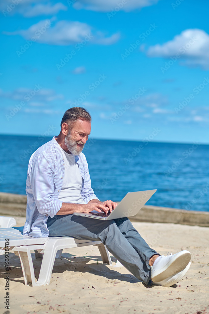 Man working on laptop on seashore