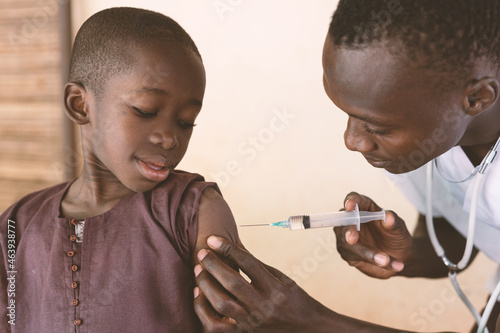 Black toddler at his first antimalarial vaccination in a small rural African dispensary photo