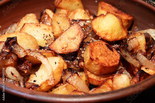 Potatoes with onion on clay plate.Closeup view.Roasted baby potatoes.Fried crispy potatoes. Cooking delicious potatoes fries in hot oil.Unhealthy and oily food. Fast food