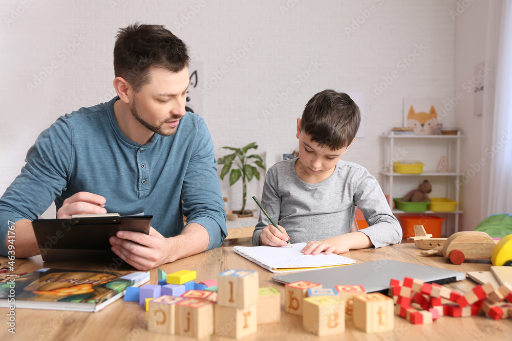 Fototapeta premium Male psychologist working with little boy in office. Autism concept