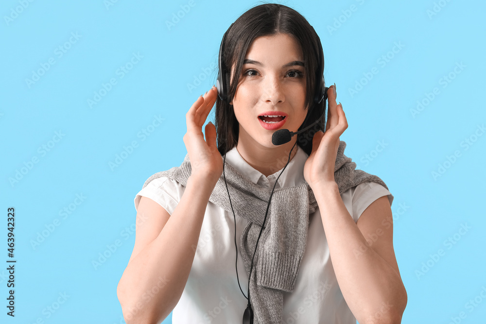 Beautiful consultant of call center in headset on blue background Beautiful consultant of call center in headset on blue background
