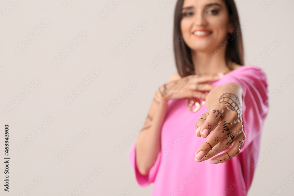 Beautiful Indian woman with henna tattoo on light background Beautiful Indian woman with henna tattoo on light background