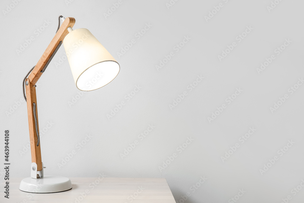 Wooden glowing lamp on table near white wall Wooden glowing lamp on table near white wall