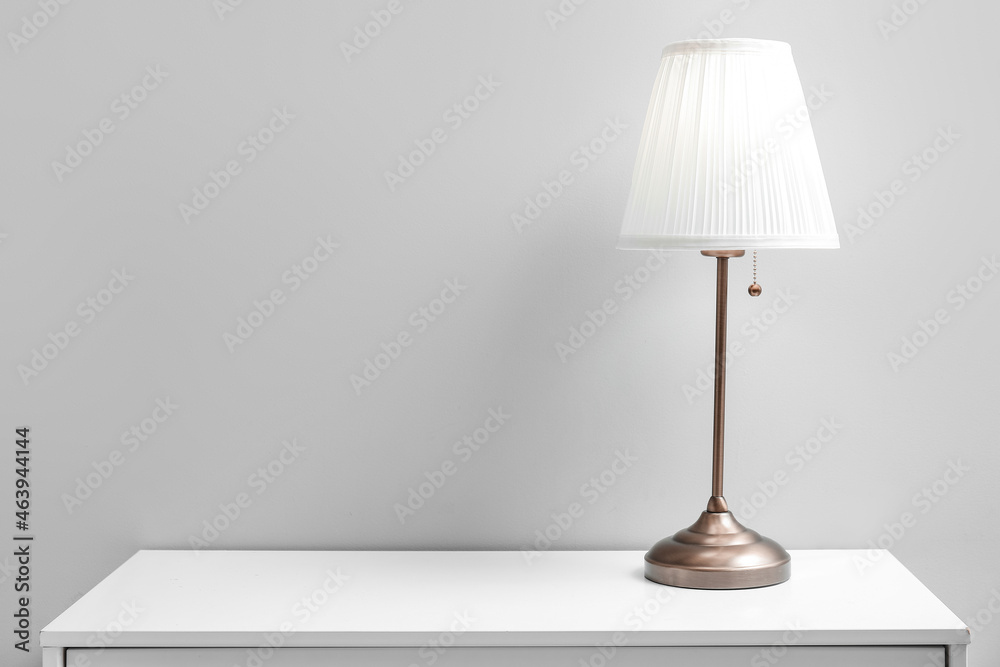 Metal lamp on shelf near light wall Metal lamp on shelf near light wall