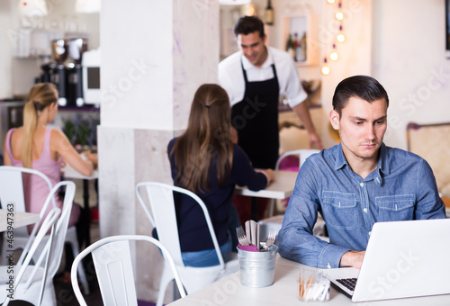 Adult man spending time in cozy tearoom with laptop