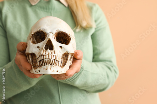 Woman holding human skull on color background © Pixel-Shot