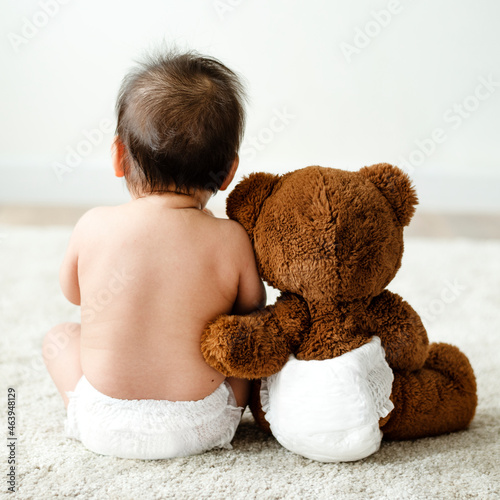Back of a baby with a teddy bear