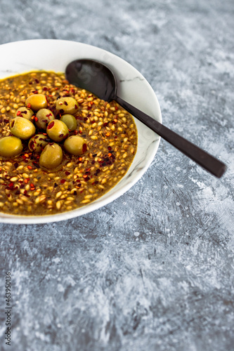 vegan spicy barley with olives and chilli flkes topping, healthy plant-based food photo