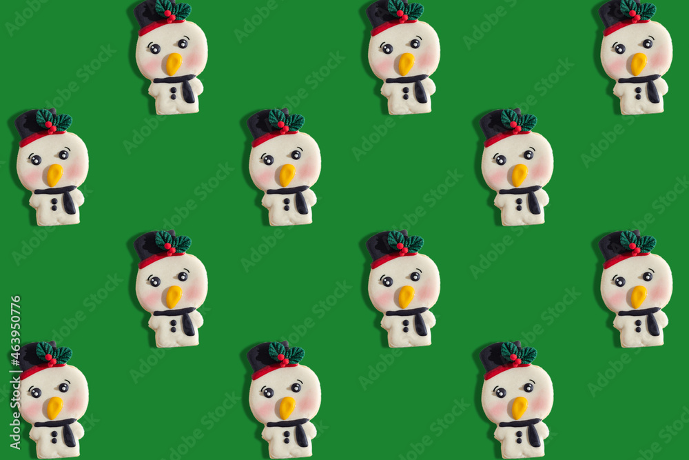 Fototapeta premium pattern of cookies in the shape of snowmen, on a flat green background
