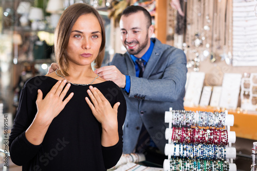 .Seller man helps to trying chainlet and pendants in the jewelry store photo