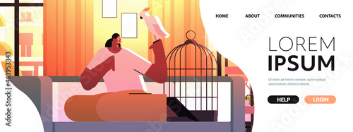 african american woman with parrot girl taking care of pet animal bird living room interior horizontal