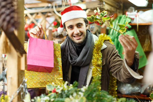 Portrait of happy young man Christmas hat with looking toys at fair outdoor