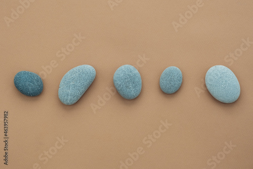 Set of sea stones of a round form on beige background. Top view of a collection of smooth pebbles.