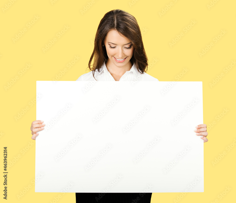 Portrait image of cheerful smiling woman in white confident wear holding showing mock up empty signboard. Businesswoman in advertising studio concept. Copy space area. Yellow color background.. Portrait image of cheerful smiling woman in white confident wear holding showing mock up empty signboard. Businesswoman in advertising studio concept. Copy space area. Yellow color background..