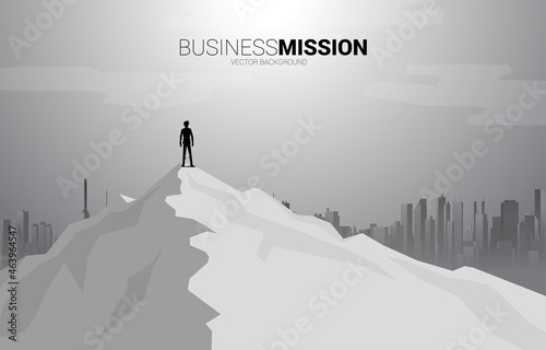 silhouette of businessman standing on the top of mountain and city background. Concept of Goal, Mission, Vision, Success in Career path.