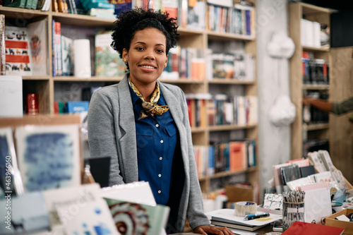 Portrait of happy black woman working in bookstore and looking at camera. photo